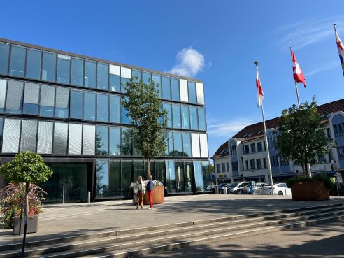 Gemeindehaus mit Baum und Fahnen